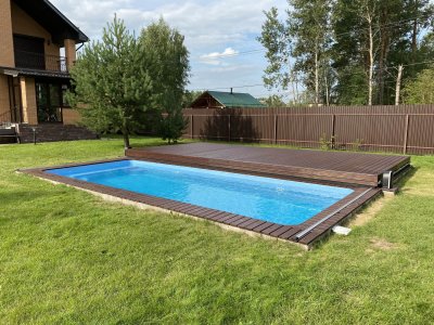 Прямоугольный бассейн с сдвижной крышкой на газоне рядом с домом